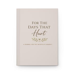May include: A light beige hardback journal with dark brown text that reads FOR THE DAYS THAT Hurt. Below the text is a small illustration of two leafy branches meeting at a central heart. The bottom text reads A JOURNAL FOR THE INFERTILITY JOURNEY.