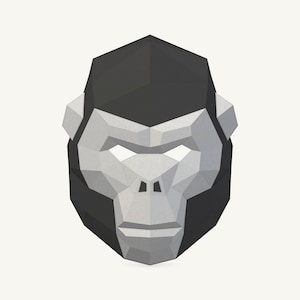 Pode incluir: Uma máscara de gorila geométrica de estilo low-poly com um design facetado. A máscara é composta por planos triangulares em cinza carvão escuro e cinza claro, criando uma representação estilizada e angular de um rosto de gorila com aberturas.