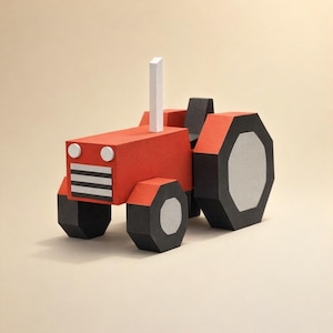 Op de afbeelding: Een rode en zwarte papieren tractor met een witte schoorsteen. De speelgoedtrekker heeft een geometrisch ontwerp, met zwarte wielen en een witte grille. Het is een speelgoed of decoratief item.