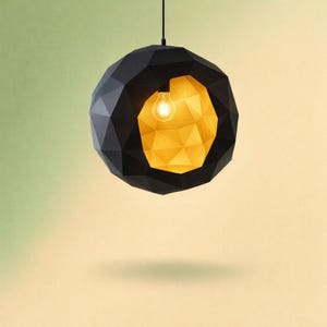 Peut inclure: Un luminaire suspendu moderne et géométrique. L'extérieur est une sphère noire mate à facettes multiples. L'intérieur est de couleur or chaud, et une seule ampoule est visible. La lumière est suspendue à un fin cordon noir.