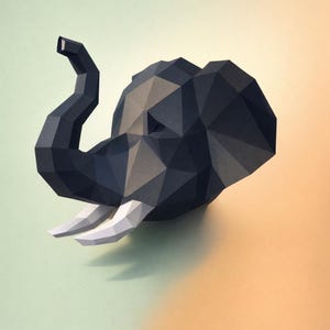Può includere: Una testa di elefante geometrica in carta nei toni del grigio e del nero, con zanne bianche. L'opera d'arte è ambientata su uno sfondo sfumato verde e arancione, creando un'estetica moderna e artistica.
