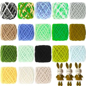 May include: A collection of colorful yarn balls in various shades, including gray, green, blue, and yellow. The yarn is arranged in neat rows, with three small bunny dolls at the bottom. The yarn appears soft and suitable for knitting or crochet projects.