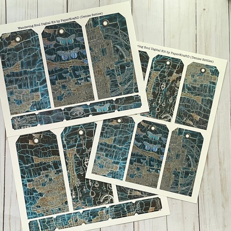 May include: A set of 10 digital printable tags with a blue and gold distressed background featuring a variety of images including butterflies, an eye, and a compass. The text "Wandering Soul Digital Kit by PaperKraftD (Denise Settles)" is printed at the top of the sheet.