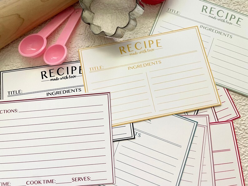May include: A set of printable recipe cards with a white background and black text. The cards have a title, ingredients, directions, time, cook time, and serves sections. The cards are decorated with a gold, red, and green border.