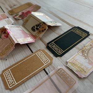 May include: A collection of vintage-style ticket stubs with gold accents and various designs, including floral patterns, a black and white animal print, and a portrait of a woman. The numbers 196609, 196620, 196624, 196625, 609961, and 196628 are visible on the tickets.