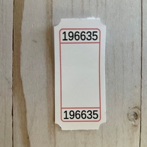 May include: White ticket with a red border and the number 196635 printed on the top and bottom.