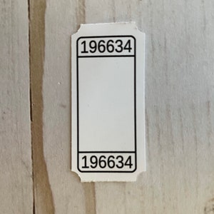 May include: White ticket with black borders and the number 196634 printed at the top and bottom.
