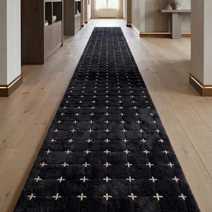 May include: A long, rectangular runner rug in a deep charcoal black colour. The surface features a repeating grid pattern formed by small, light beige cross-stitch details at each intersection, creating a textured, uniform appearance across the rug.
