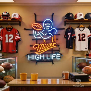 May include: A Miller High Life neon sign featuring a football player graphic mounted on a black metal rack. The display includes red and white football jerseys with the number 12, sports caps, and several brown leather footballs on glass shelves.
