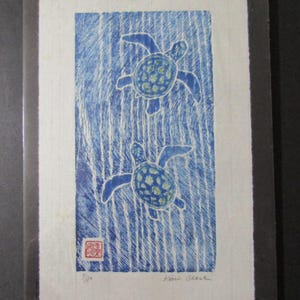 May include: A blue and white print depicting two sea turtles against a background of vertical stripes. The turtles' shells have green detailing. The print is signed "Kevin Clark" and numbered "7/50".
