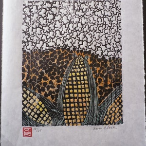 May include: A black and white woodblock print of corn stalks with a yellow and orange corn cob. The print is signed "Koren Clark" and numbered "14/165".