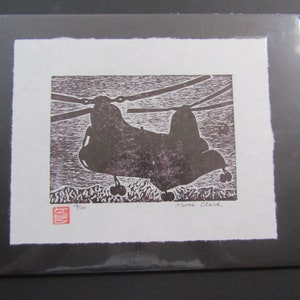 May include: A black and white woodblock print of a helicopter in flight. The print is signed "Kevin Clark" and numbered "3/100".