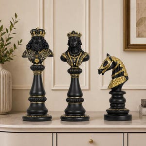 Peut inclure: Trois bustes décoratifs noirs et dorés sur le thème des échecs. Les bustes comprennent un roi, une reine et un cavalier. Le roi et la reine sont des bustes avec des couronnes et des détails ornés. Le cavalier est une tête de cheval.