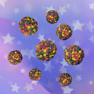 May include: An image of several colorful, spherical objects, each composed of many smaller, round pieces. The objects are in shades of red, yellow, green, and purple. The background is a gradient of purple and blue with white star shapes.