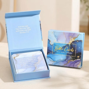 May include: A light blue box containing 50 Bible cards with a purple, blue, and gold marble pattern. The box lid interior features the text And God said, Let there be light, and there was light. Genesis 1:3. The cards feature Bible verses.