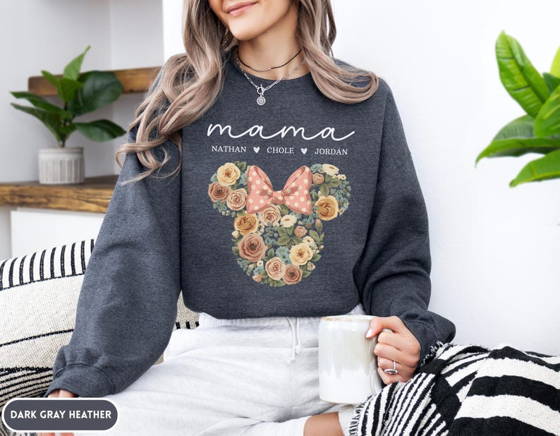 May include: Dark gray heather sweatshirt with the word "mama" in script. Below the word "mama" are the names Nathan, Chole, and Jordan. The sweatshirt features a floral Mickey Mouse head design with a pink bow.
