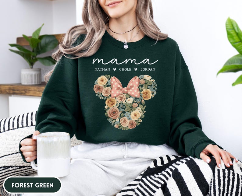May include: Forest green sweatshirt with the word "mama" in script. Below the word "mama" are the names Nathan, Chole, and Jordan. A floral Mickey Mouse head design with a pink bow is on the front.