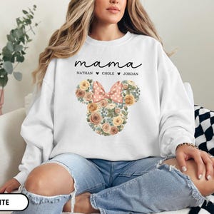 May include: White sweatshirt with the word "mama" in script above the names Nathan, Chole, and Jordan. A floral Mickey Mouse head design with a pink polka dot bow is featured on the front.