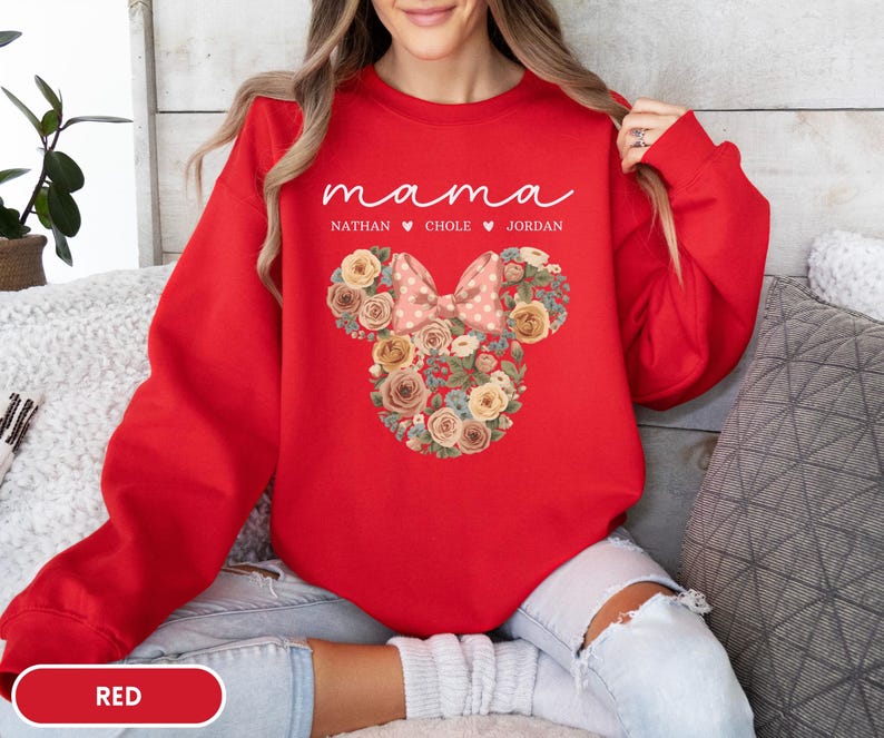 May include: A red sweatshirt with the word "mama" in white script. Below the word "mama" are the names Nathan, Chole, and Jordan. A floral Minnie Mouse design is in the center of the sweatshirt.