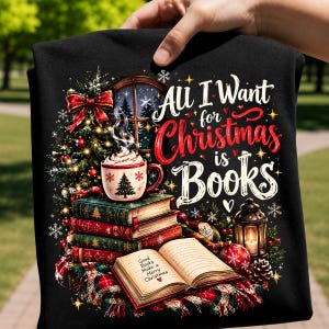 Peut inclure: Un t-shirt noir avec une illustration représentant une pile de livres, une tasse de chocolat chaud, une lanterne allumée et un sapin de Noël. Le texte indique All I Want for Christmas is Books et le livre ouvert Good Books Make a Merry Christmas.