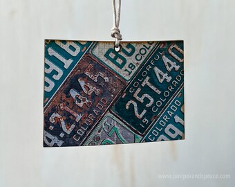 May include: A rectangular sign made of repurposed license plates. The sign features a collage of vintage Colorado license plates with various numbers and the words "COLORADO" and "COLORFUL".