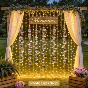Puede incluir: Un fondo fotográfico de madera con cortinas color crema, guirnaldas de luces blancas cálidas y fotografías cuadradas colgantes. Un letrero de madera con la palabra Memories está centrado en la parte superior, decorado con eucalipto verde.