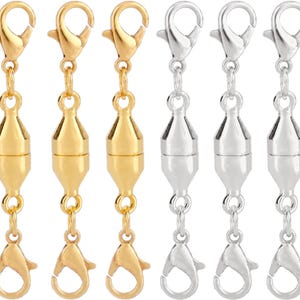 May include: A collection of gold and silver-colored magnetic clasps. Each clasp features a lobster claw clasp connected to a cylindrical magnetic closure. The clasps are designed for jewelry making and crafting.