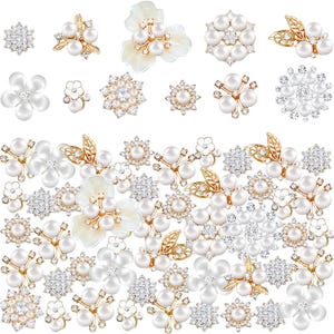 Puede incluir: Un surtido de adornos florales decorativos. La colección incluye varios diseños con perlas de imitación, pedrería transparente y detalles metálicos dorados. Los adornos tienen forma de flores, hojas y estrellas, perfectos para manualidades o accesorios.