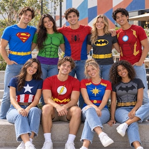 Op de afbeelding: Een groep van negen personen draagt diverse T-shirts met superheldenthema's, waaronder ontwerpen van Superman, Hulk, Spider-Man, Batman, Iron Man, Captain America, The Flash, Captain Marvel en een donkergrijs Batman-logo T-shirt, gecombineerd met spijkerbroeken.