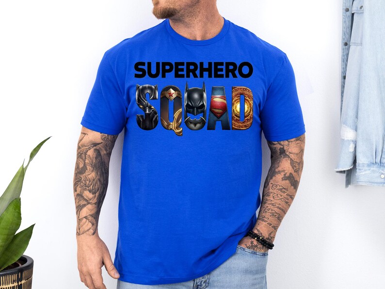 Puede incluir: Camiseta azul real con las palabras "SUPERHERO SQUAD" en negro. La palabra "SQUAD" presenta logotipos de superh&eacute;roes. La camiseta es de manga corta y est&aacute; hecha de un material suave.