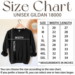 Puede incluir: Sudadera negra unisex Gildan 18000 colgada en una percha. Una tabla de tallas muestra medidas en pulgadas para las tallas S a 5XL. El texto dice "Size Chart" y "UNISEX GILDAN 18000".
