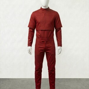 May include: A red jumpsuit displayed on a mannequin. The outfit features a high collar, long sleeves, and a cropped top layer. The pants are fitted, and the overall design has a futuristic aesthetic. The mannequin is white, and the background is plain.