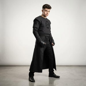 Puede incluir: Un atuendo negro que consta de un top corto con un diseño geométrico, una camiseta interior de manga larga, un abrigo largo, pantalones y guantes. El atuendo es completamente negro y parece estar hecho de una tela texturizada. La persona lleva zapatos negros.