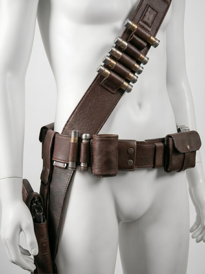 K&ouml;nnte beinhalten: Ein brauner Leder-G&uuml;rtel und Schulterriemen mit Patronenhaltern und Taschen aus Metall. Der G&uuml;rtel hat eine Halterung f&uuml;r eine Schusswaffe. Das Zubeh&ouml;r ist f&uuml;r ein Western- oder Cosplay-Thema konzipiert.