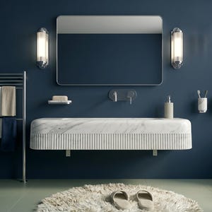 May include: A modern bathroom with a navy blue wall, a marble sink, and a large mirror. The room features a chrome towel rack with towels, wall sconces, and a fluffy rug. The floor is a light green color.