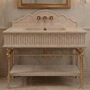 May include: A beige travertine stone bathroom vanity featuring a scalloped backsplash, a fluted front apron, and a lower shelf. The vanity is supported by a metallic gold-toned metal frame with four legs and includes a matching gold-toned faucet.