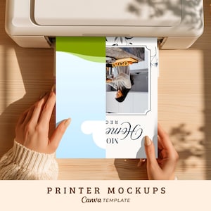May include: A white printer outputting a sheet of paper with a graphic design. The paper features a light blue and green abstract shape, a rectangular photo of a person in a kitchen, and the text "Home Recipes" printed in a black script font.