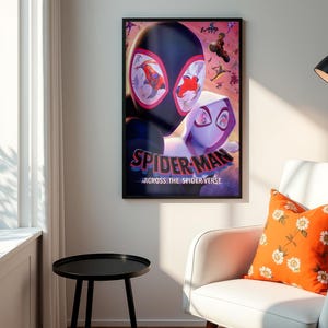 May include: A framed poster featuring Spider-Man and Spider-Gwen from "Across the Spider-Verse." The poster has a black frame and is hanging on a white wall. An orange floral pillow rests on a white armchair. A black side table is in the foreground.