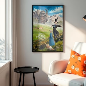 Puede incluir: Un p&oacute;ster enmarcado de "El castillo ambulante" cuelga de una pared. La obra de arte representa personajes en un paisaje verde con un castillo al fondo. El p&oacute;ster est&aacute; en un marco negro. Un coj&iacute;n naranja con flores descansa sobre una silla blanca.