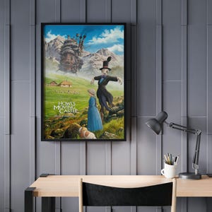 Puede incluir: P&oacute;ster enmarcado con arte de la pel&iacute;cula animada "El castillo ambulante". La imagen muestra una escena caprichosa con un castillo, personajes y texto. El p&oacute;ster se exhibe en una pared gris sobre un escritorio de madera.