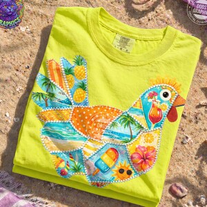 May include: A folded, neon yellow t-shirt featuring a colorful patchwork design of a chicken. The chicken design incorporates tropical elements like pineapples, palm trees, and a popsicle. The shirt has a Comfort Colors tag.