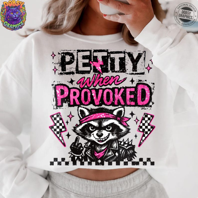 May include: White sweatshirt with the text "PETTY when PROVOKED" in black and pink. A raccoon graphic with a pink bandana and leather jacket is featured. The design includes lightning bolts and stars.