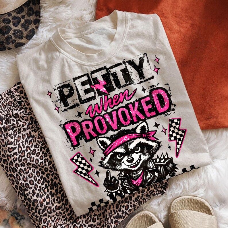 May include: Off-white t-shirt with the text "Petty When Provoked" in black and pink. The shirt features a raccoon graphic wearing a bandana and a leather jacket. Leopard print pants and a leopard print hat are also visible.