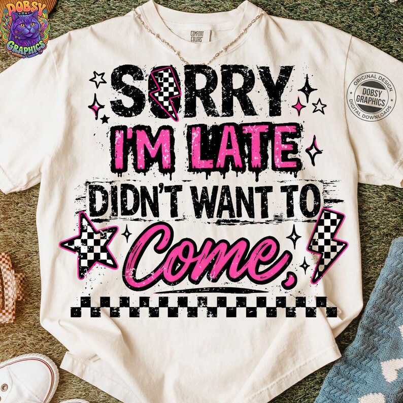May include: Cream-colored t-shirt with the text "SORRY I'M LATE DIDN'T WANT TO COME" in black and pink. The design includes stars, a checkered lightning bolt, and a checkered border at the bottom. A necklace is visible.