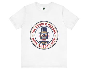 May include: A white short-sleeve t-shirt featuring a circular graphic on the chest. The design includes a blue robot wearing a top hat, surrounded by the red text "THE ROBBER BARONS HAVE ROBOTS NOW." with two small gold stars on the sides.