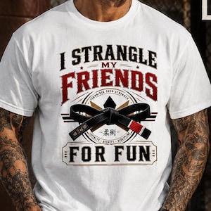 May include: A white short-sleeve t-shirt featuring a graphic with the text I STRANGLE MY FRIENDS FOR FUN. The design includes a black martial arts belt, a circular emblem with the words TECHNIQUE OVER STRENGTH, LOYALTY, RESPECT, DISCIPLINE.