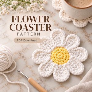 Può includere: Uno schema per sottobicchiere a fiore all'uncinetto in download PDF con un sottobicchiere a forma di margherita bianco e giallo, un gomitolo di lana bianca e un uncinetto in legno. Il testo recita FLOWER COASTER PATTERN e PDF Download.