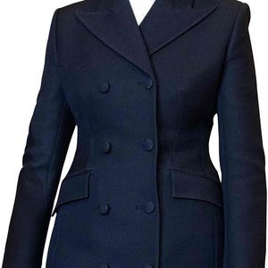 Op de afbeelding: Een marineblauwe double-breasted blazer met een getailleerde pasvorm. De blazer heeft zes knopen, twee voorzakken en een wit overhemd met kraag eronder. De lengte van de jas reikt tot halverwege de dij.