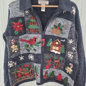 Peut inclure: Un gilet zippé bleu foncé avec un motif patchwork brodé de décorations de Noël, notamment un poinsettia, un cardinal, un traîneau avec des cadeaux, des chaussettes, un chalet et des flocons. L'étiquette indique Heirloom Collectibles.