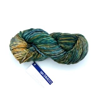 May include: A skein of thick, hand-dyed yarn featuring a variegated color palette of deep teal, forest green, and golden ochre. A white rectangular tag is attached to the yarn, displaying the text 190 DRACO in bold blue capital letters.